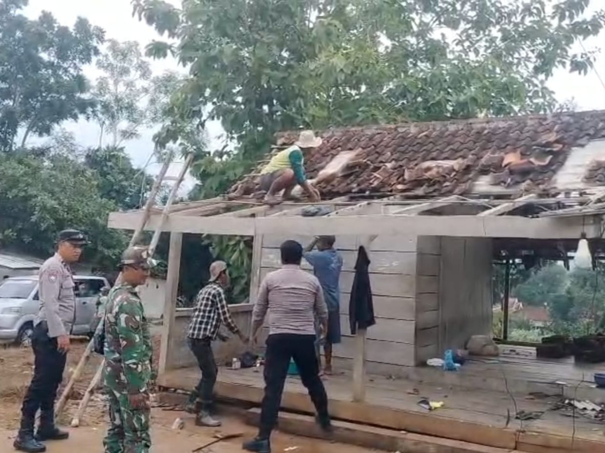 Personel Polsek dan Koramil Guluk-Guluk bersama warga setempat membersihkan sisa-sisa kerusakan bangunan yang diterjang angin puting beliung, Senin (22/12). (Ist)